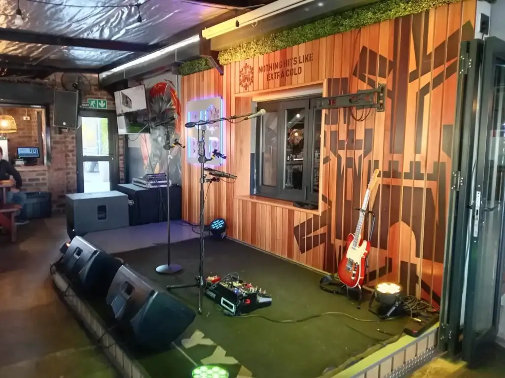 Indoor venue stage with microphones, guitar and lighting
