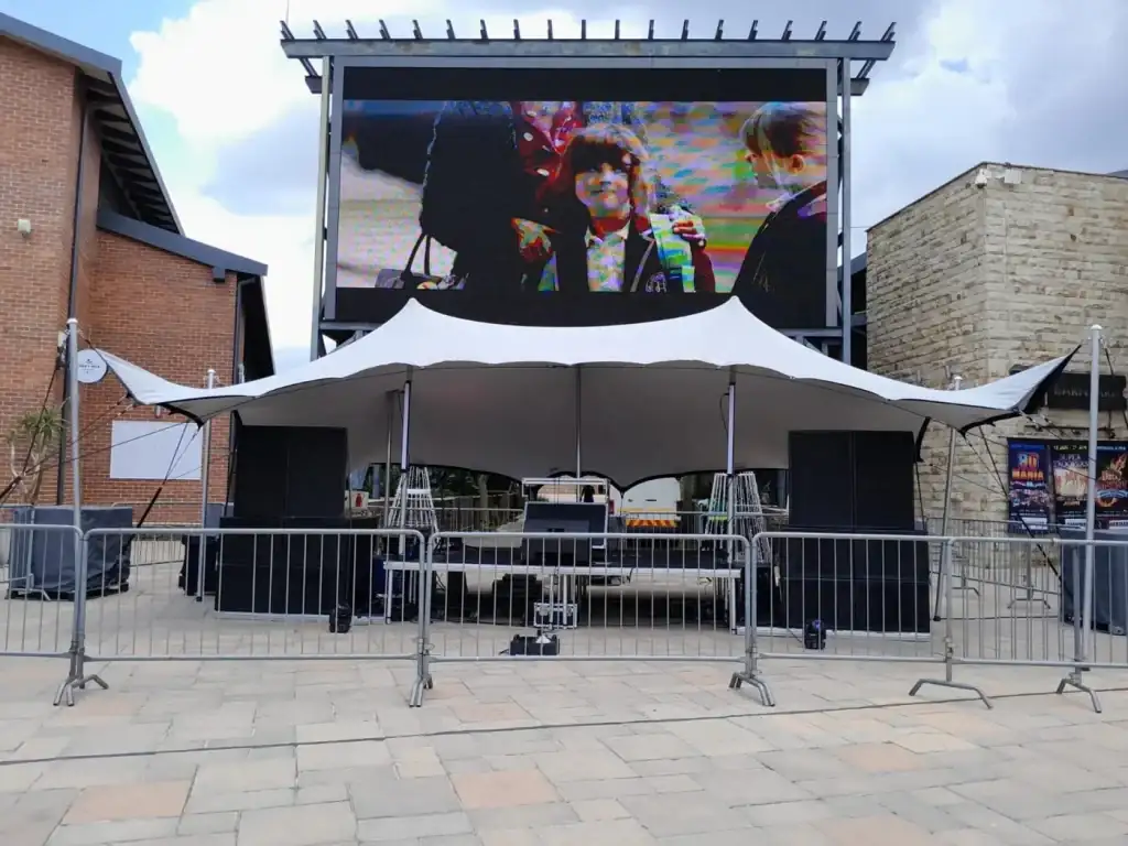 Stretch-tent stage with an LED screen and sound system in a plaza